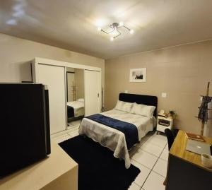 a bedroom with a bed and a desk and a television at Hostel Londrina I in Londrina