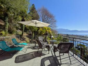 a patio with chairs and a table and an umbrella at Villa Angelina - Lake View Dreams in Cannero Riviera