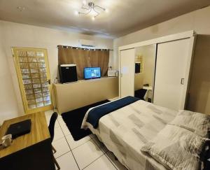 a bedroom with a bed and a desk and a television at Hostel Londrina I in Londrina
