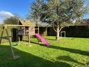 a playground with a pink slide and a tree at Villa Rose in Graignes
