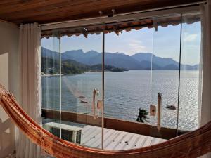 a hammock in a room with a view of the water at Recanto Vista Mar - Costa Verde, Mangaratiba in Mangaratiba