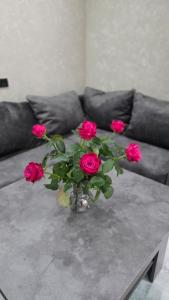 a vase of roses on a table with a couch at Livana Guesthouse - Goris in Goris +15 photos