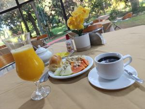 a table with a plate of food and a cup of orange juice at Hotel Sancer in Coronel Oviedo