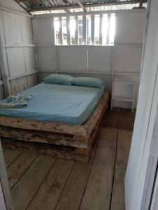 a bed in a room with a wooden floor at Cabaña Luna Nueva in Buenaventura