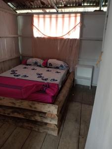 a bed in a small room with a window at Cabaña Luna Nueva in Buenaventura