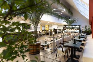 a restaurant with tables and chairs and plants at Art Hotel superior in Zalakaros