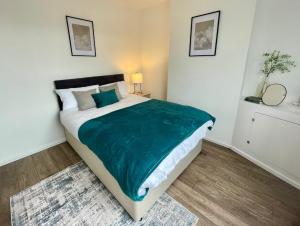 a bedroom with a large bed with a green blanket at Petal House, Gloucester - Large, Spacious and charming in Gloucestershire