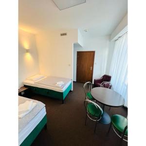 a room with a bed and a table and chairs at Hotel pod Dębem in Szydłowiec