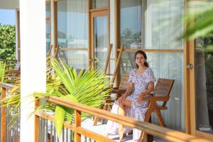 a woman in a dress sitting on a porch at Lagoon Villa Maldives in Thoddoo