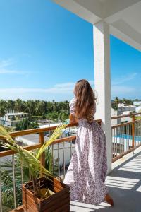 a woman sitting on a balcony looking out at the ocean at Lagoon Villa Maldives in Thoddoo