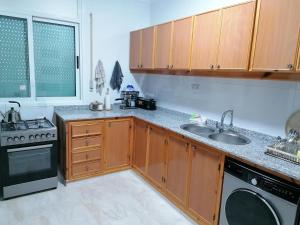 a kitchen with wooden cabinets and a sink and a stove at Résidences nour nador in Nador +2 photos