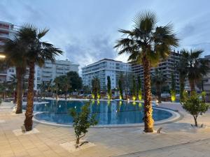 a swimming pool with palm trees in a city at Casa Del Sol - Shengjin in Shëngjin