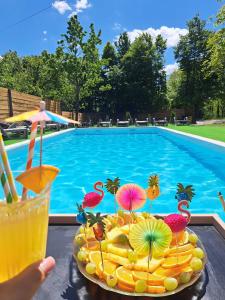 a plate of food with a drink next to a swimming pool at Apartments Villa Mavi Plitvice in Drežnik Grad
