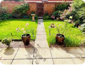 a garden with two potted plants in the grass at 3 Bed Home, Exeter, Devon in Countess Wear