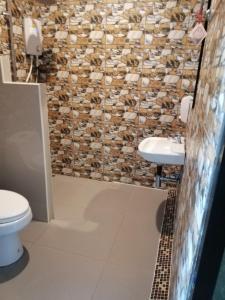 a bathroom with a stone wall and a toilet and sink at โรงแรมเพ็ญวิวรีสอร์ท Phenview resort in Amphoe Phen +20 photos