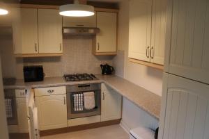 a kitchen with white cabinets and a stove top oven at 3 Bed Home, Exeter, Devon in Countess Wear