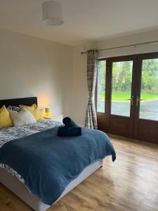 a bedroom with a bed with a blue blanket and a window at The Cuckoos Nest - 2 bedroom in Headford
