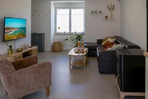 a living room with a couch and a tv at Azur Cancale in Cancale
