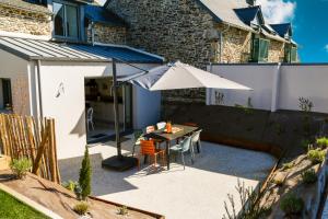 a patio with an umbrella and a table and chairs at Azur Cancale in Cancale