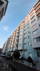 a tall apartment building with cars parked in front of it at Apartament COSTA in Mamaia