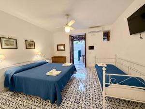 a bedroom with two beds with blue sheets and a tv at La Casa al Mare Vulcano in Vulcano