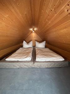 a bed in a wooden room with two pillows at Ferienwohnung Insel Malchow mit eigenem Bootsanleger in Malchow
