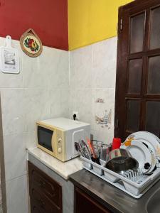 a kitchen counter with a microwave and a dish rack at Quarto individual- Espaço Casa Mendes in Praia