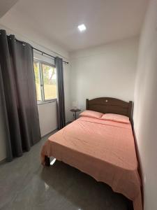 a bedroom with a bed with a red blanket and a window at Quarto individual- Espaço Casa Mendes in Praia