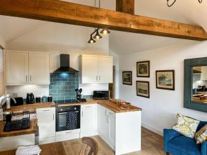 a kitchen with white cabinets and a blue couch at South Downs Lodge in Soberton
