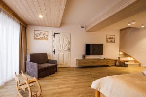 a living room with a couch and a television at Rogata Chata Tatra View & Jacuzzi in Kościelisko
