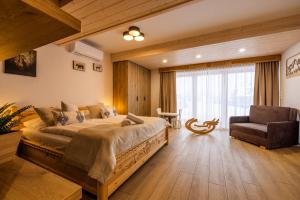 a bedroom with a large bed and a chair at Rogata Chata Tatra View & Jacuzzi in Kościelisko