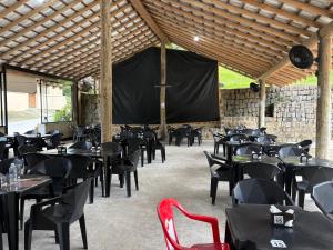a restaurant with black tables and chairs and a stage at Pousada - Aconchego da tia Zeni in Mangaratiba