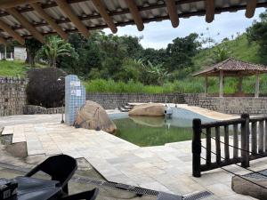 a pool of water in a yard with a fence at Pousada - Aconchego da tia Zeni in Mangaratiba