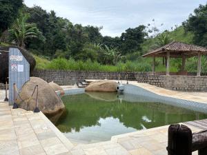 a pool of water with rocks and a gazebo at Pousada - Aconchego da tia Zeni in Mangaratiba +7 photos