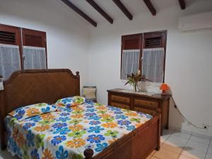 a bedroom with a bed and a dresser and windows at Villa DAMARRE in Petit-Bourg