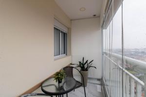 a small balcony with a glass table and a window at Lovely Studio - GRU 1613 in Guarulhos