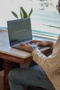 a man sitting at a table using a laptop computer at Hotel Boutique Plaza Doradas in San José del Cabo