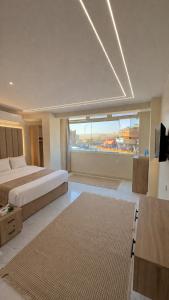 a large bedroom with a bed and a large window at Tua Pyramids View in Cairo