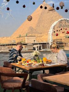 a man and woman sitting at a table with food at Tua Pyramids View in Cairo