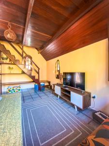 a living room with a wooden ceiling and a staircase at Chalé Espaço Raiz de Lumiar in Nova Friburgo