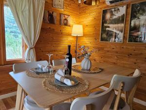 a wooden dining room table with chairs and a bottle of wine at Pond View Cabin in Būda