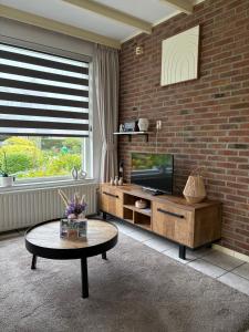 a living room with a television and a brick wall at Appartementen Koets in Biggekerke +11 photos