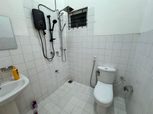 a white tiled bathroom with a toilet and a sink at Journy B Holiday Inn Ekala in Ekala