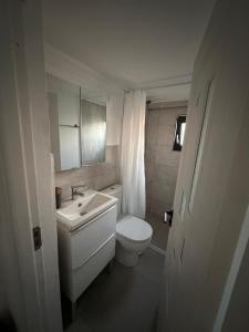 a white bathroom with a toilet and a sink at Casa IRI - plaja Corbu in Corbu
