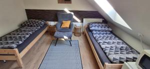 an attic room with two beds and two chairs at Takács Vendégház 2 in Sopron
