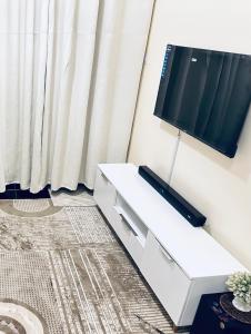 a living room with a tv and a white dresser at ZulynHomes in Kisumu