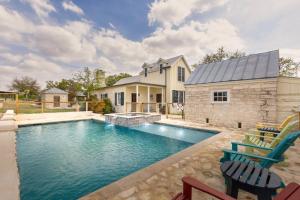 a swimming pool with two chairs and a house at 7Cs Sunset Valley Ranch in Fredericksburg