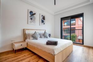 a white bedroom with a large bed and a window at Noria Golf Apartment in Marrakesh