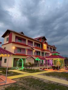 a hotel with a building with tables and umbrellas at Dev Murti Eco Resort in Chālsa Mahābāri