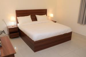 a bed in a room with two night stands and two lamps at شقق نور الفخامه المخدومه in Buraydah